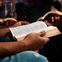 three people reading Bibles