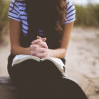 Woman praying with Bible on her lap