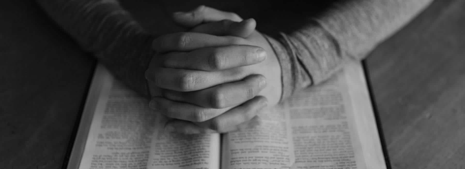 praying hands on a Bible