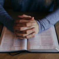 praying hands on a Bible