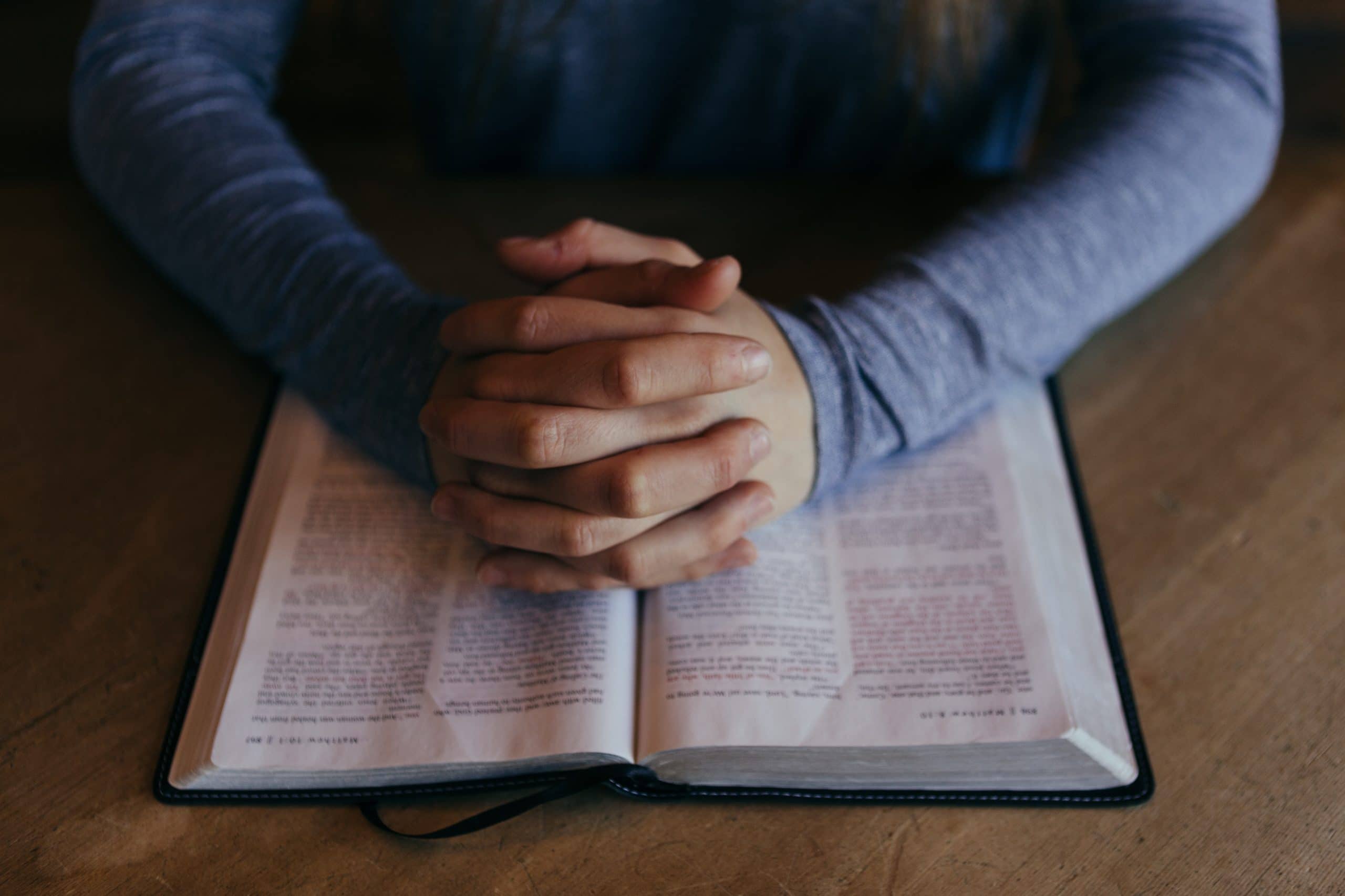 praying hands on a Bible