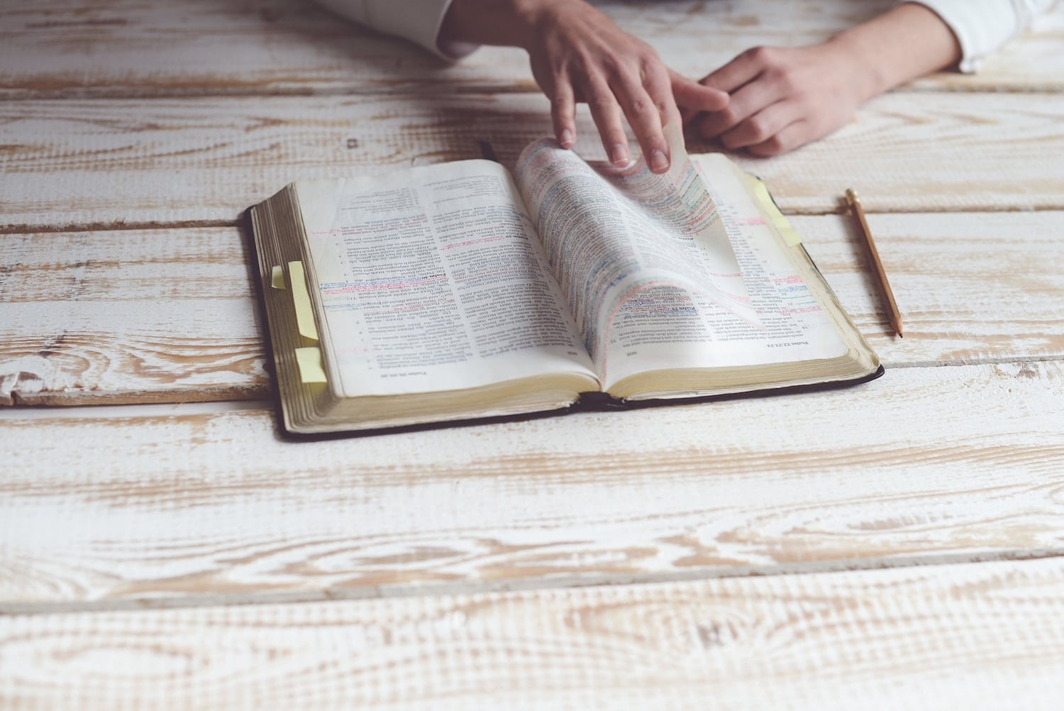 Statement of Faith | The Navigators | hands flipping through a bible on a wooden desk