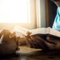 Praying the Names and Attributes of God | The Navigators Prayer Resource | Two young man praying and reading Bible at home