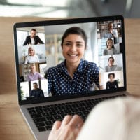 Laptop screen over woman shoulder view during group online communication