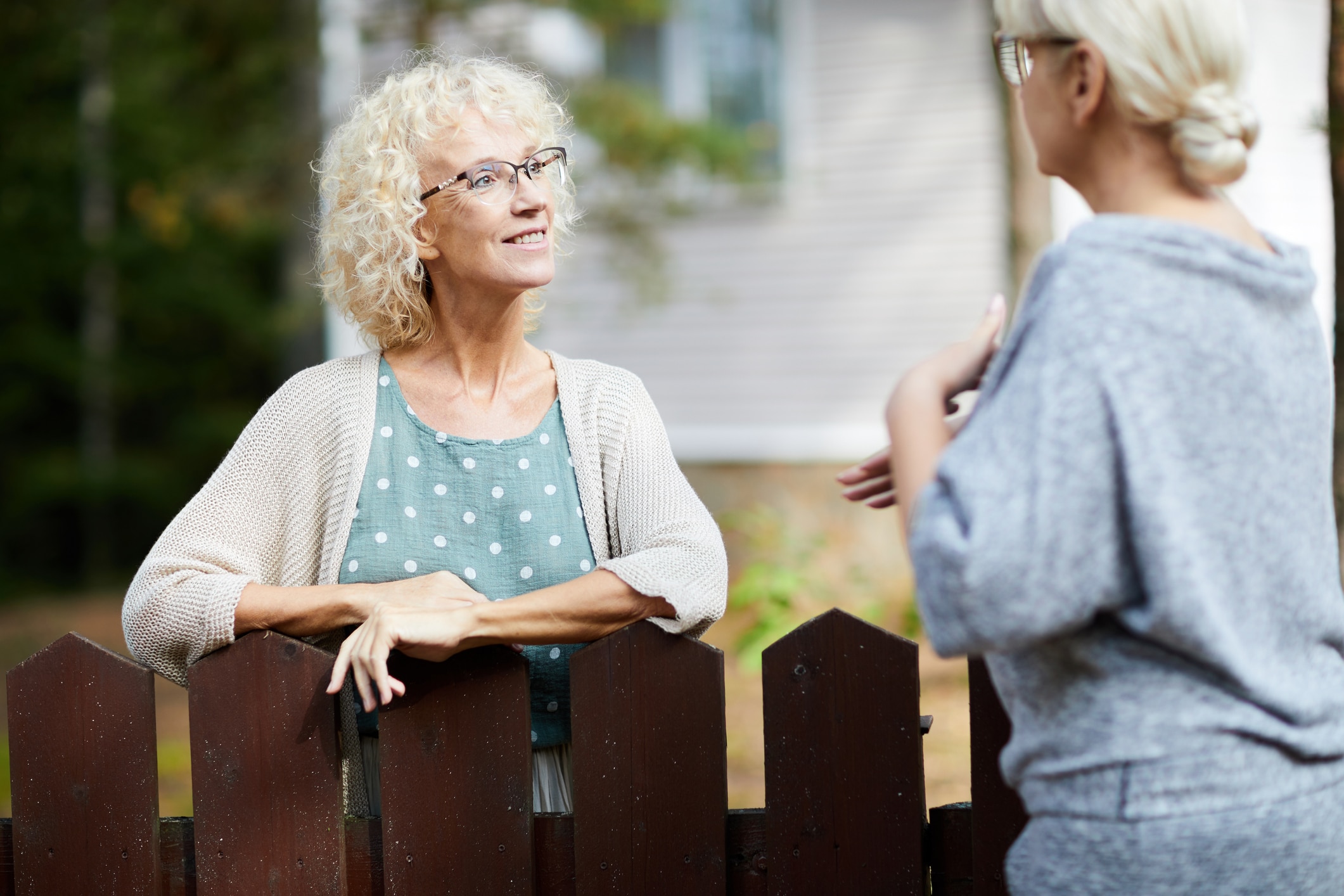 Share God's Love With Your Neighbors | Two mature female neighbours talking through fence about everyday life