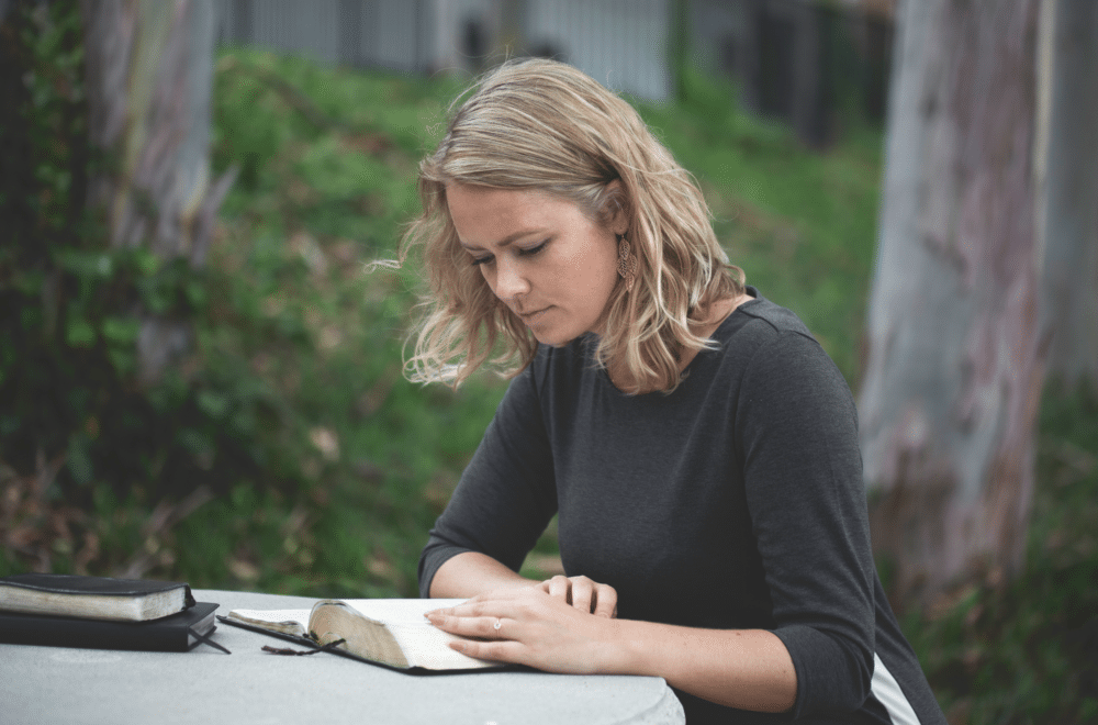 Young woman reading the Bible in a forested area
