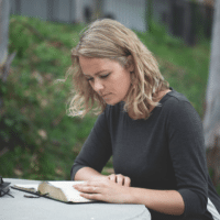 Young woman reading the Bible in a forested area