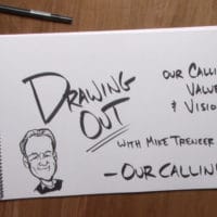 A piece of notebook paper on a wooden table with a sketch and words that read, "Drawing out our calling."