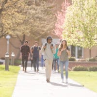 A college-aged man and woman walk across campus to their next class.