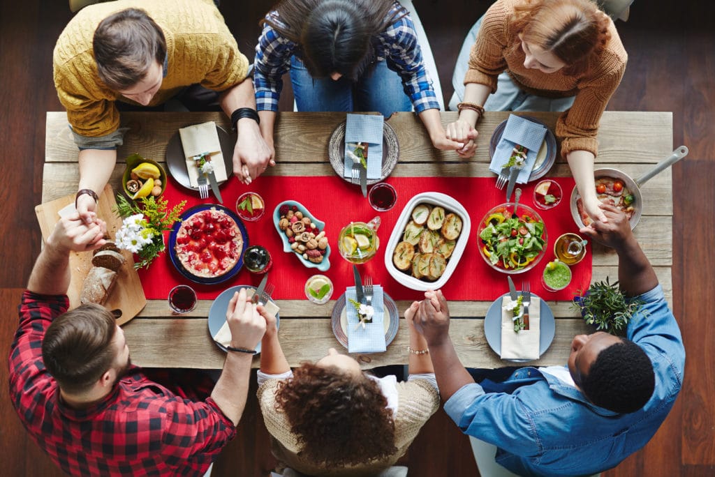 Becoming a Disciplemaker | The Navigators | friends enjoying a thanksgiving meal together at a wooden table