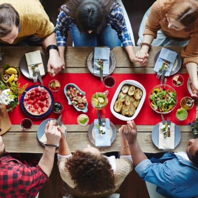 Becoming a Disciplemaker | The Navigators | friends enjoying a thanksgiving meal together at a wooden table
