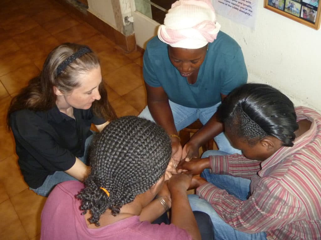 Lydia Klingforth praying with women she mentors in Kenya