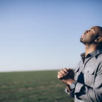 Praying for Our Nation and Leaders | Navigators Prayer Resource | Man with clasped hands in prayer in a field