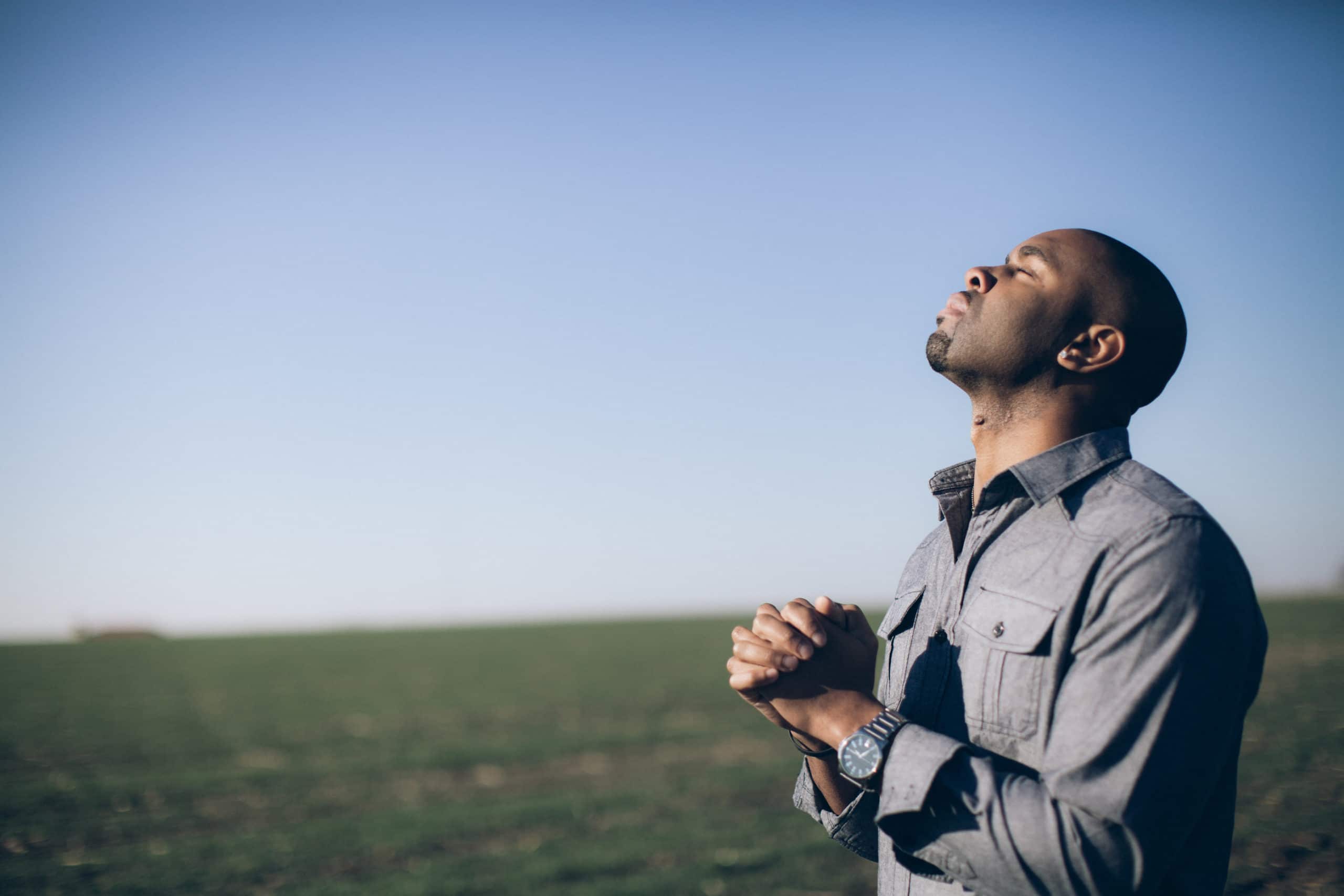 Praying for Our Nation and Leaders | Navigators Prayer Resource | Man with clasped hands in prayer in a field