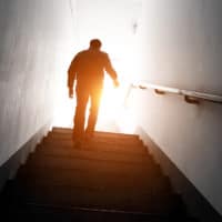 Finding Hope in Hard Times | Man walking upstairs into the light.