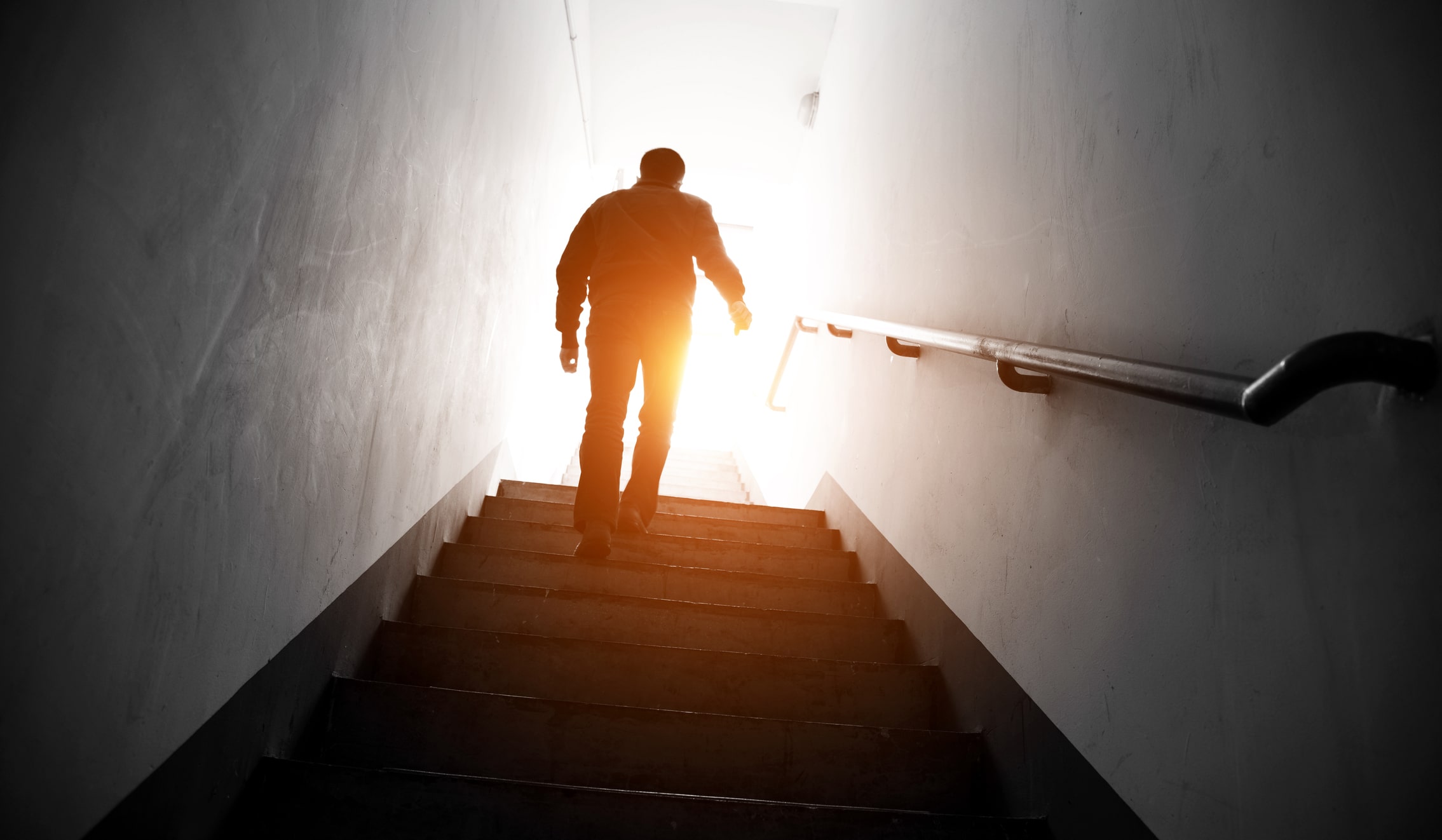Finding Hope in Hard Times | Man walking upstairs into the light.