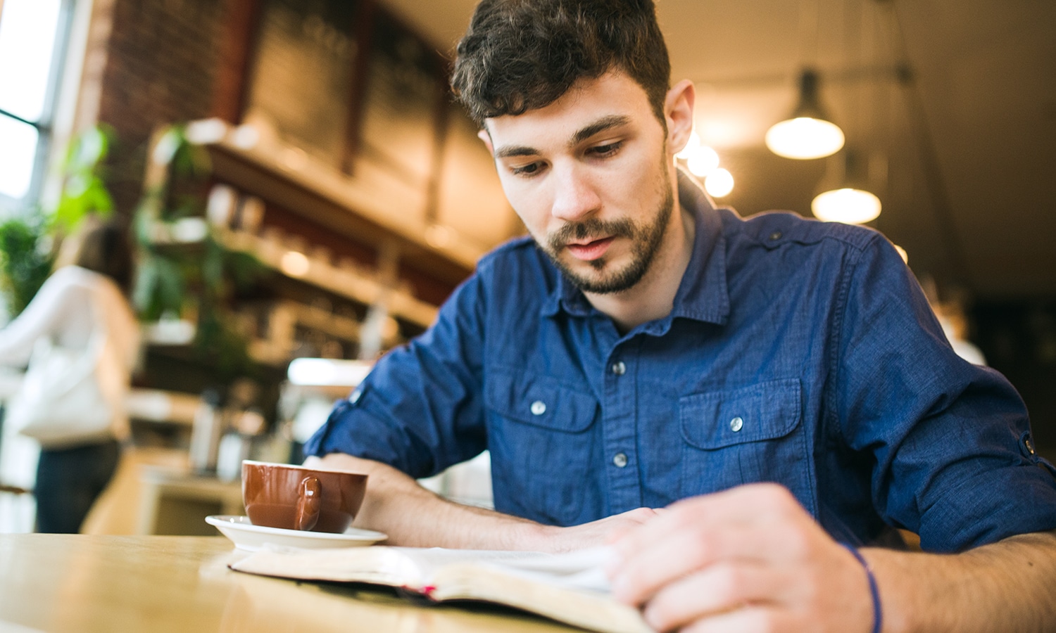 Assurance of Salvation Bible Study | Navigators Bible Study Resource | Young man reading a book at a coffee shop