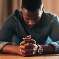 Overcoming Obstacles to Prayer: An Interview With Jarrett Stevens | The Navigators Navpress | young businessman sitting with his hands together in his home office and praying