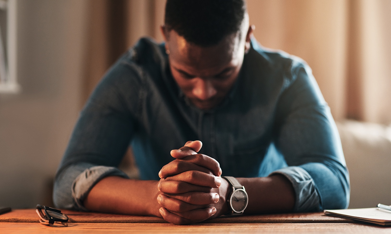 Overcoming Obstacles to Prayer: An Interview With Jarrett Stevens | The Navigators Navpress | young businessman sitting with his hands together in his home office and praying