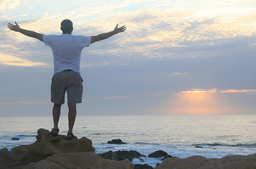 Experience the Life-Giving Love of Jesus | Navpress | Man praisng on the beach in the morning
