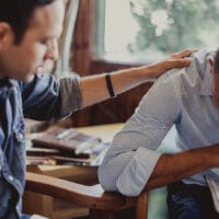 One man praying over another who is going to the nations. They are sitting at a kitchen table.