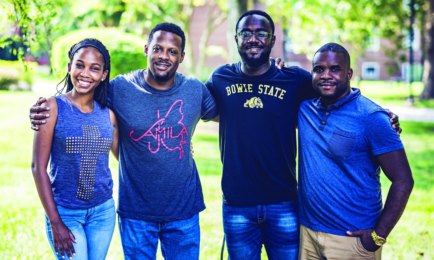 Four young adults at Bowie State University posing for a picture in a park, surrounded by trees.
