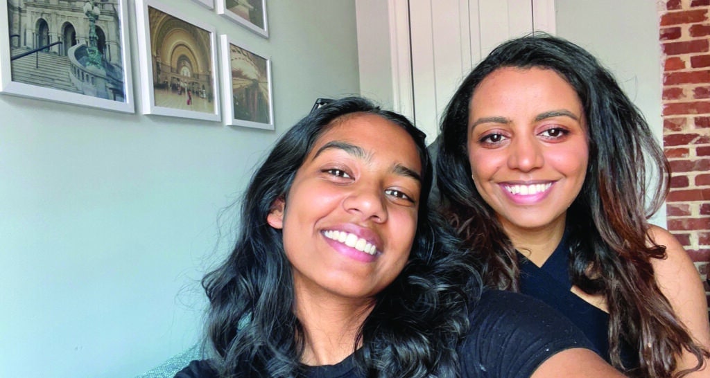 Sharon and Betsida, two women, pose for a selfie in a dorm room.