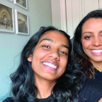 Sharon and Betsida, two women, pose for a selfie in a dorm room.