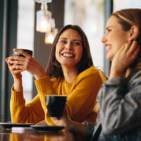 Two women meeting in a coffee shop while one shares their faith with another.