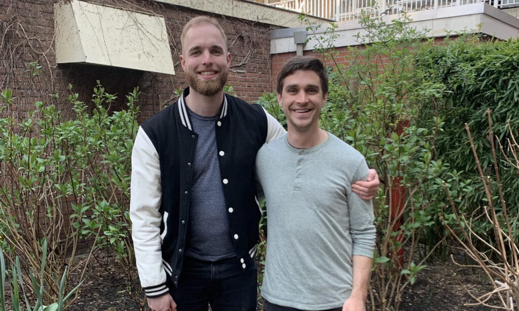 Every and Scott post for a picture in front of a building with shrubs.