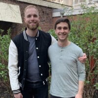 Every and Scott post for a picture in front of a building with shrubs.