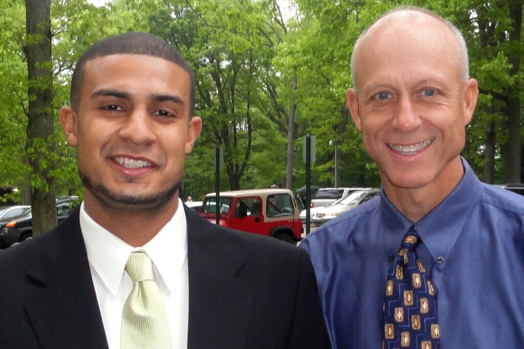 Two well-dressed men, Aaron Collier and Henry Bouma, pose for a photo in a park.