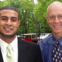 Two well-dressed men, Aaron Collier and Henry Bouma, pose for a photo in a park.