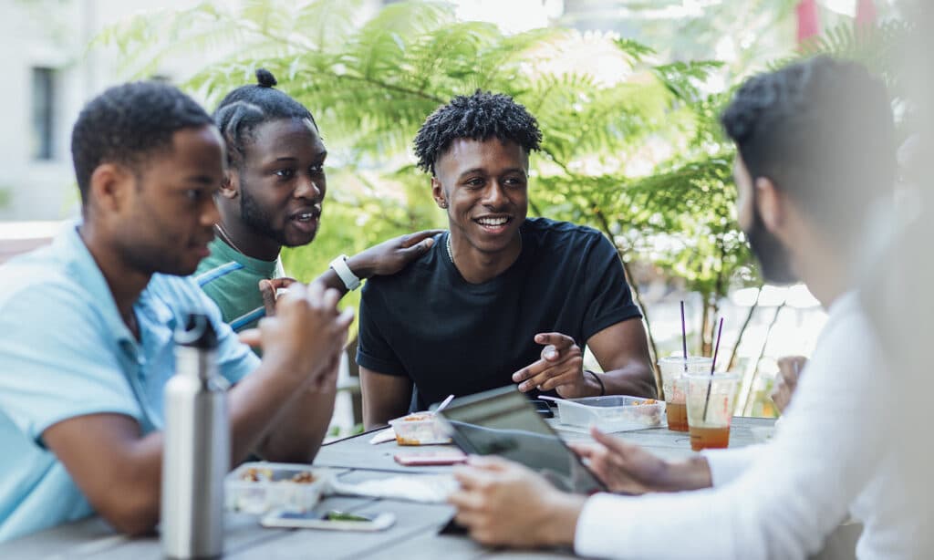Four young men sitting around a table engaging in Life-to-Life Discipleship.