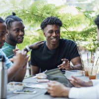 Four young men sitting around a table engaging in Life-to-Life Discipleship.