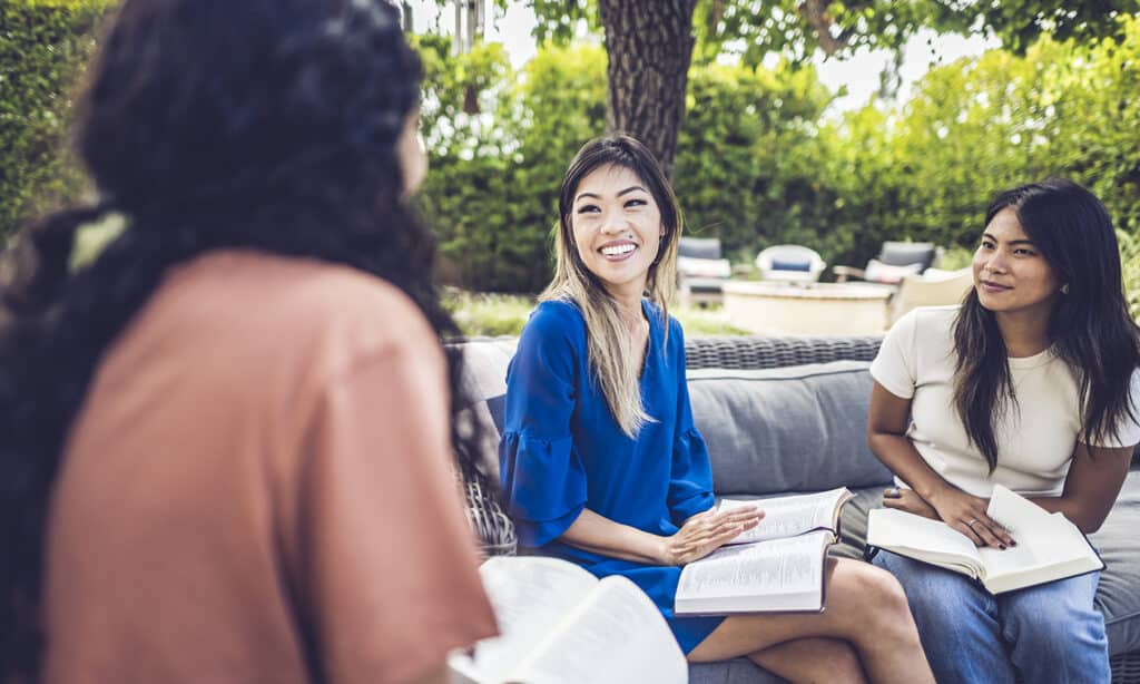 Alice Matagora, an author of How to Save The World, talking with two other disciplemakers about discipleship while sitting on outdoor patio furniture.