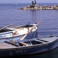 Three docked canoe-style fishing boats floating in the water.