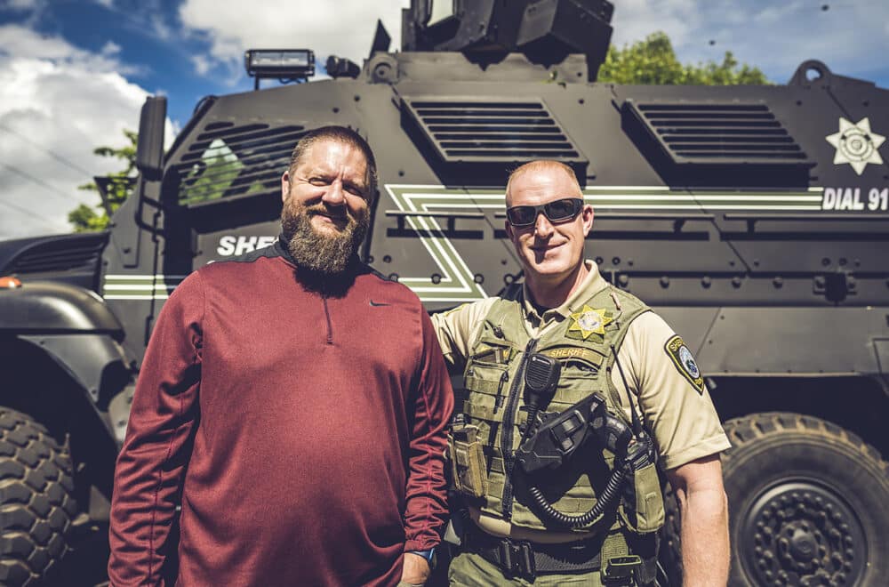 Chris Green, the founder of The Navigators First Response Ministry, standing in front of an armed vehicle with another police officer.