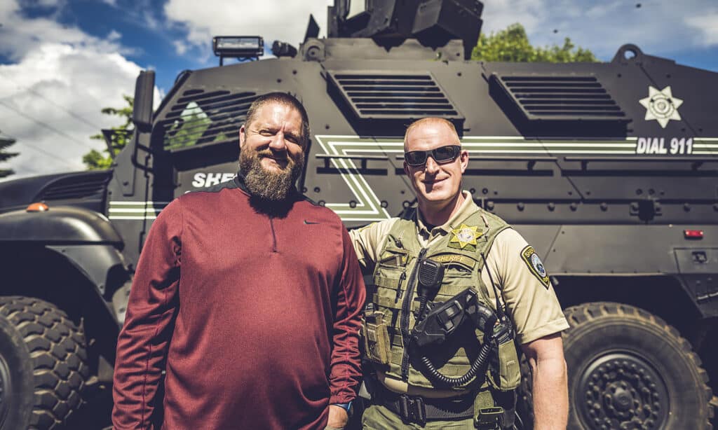 Chris Green, the founder of The Navigators First Response Ministry, standing in front of an armed vehicle with another police officer.