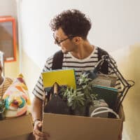 College students moving in dorm. They are carrying boxes.