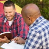 Men having a bible study on a camping trip.