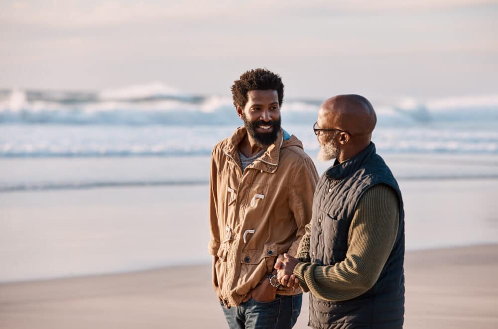 Shot of a young man going for a walk along the beach with his mentor