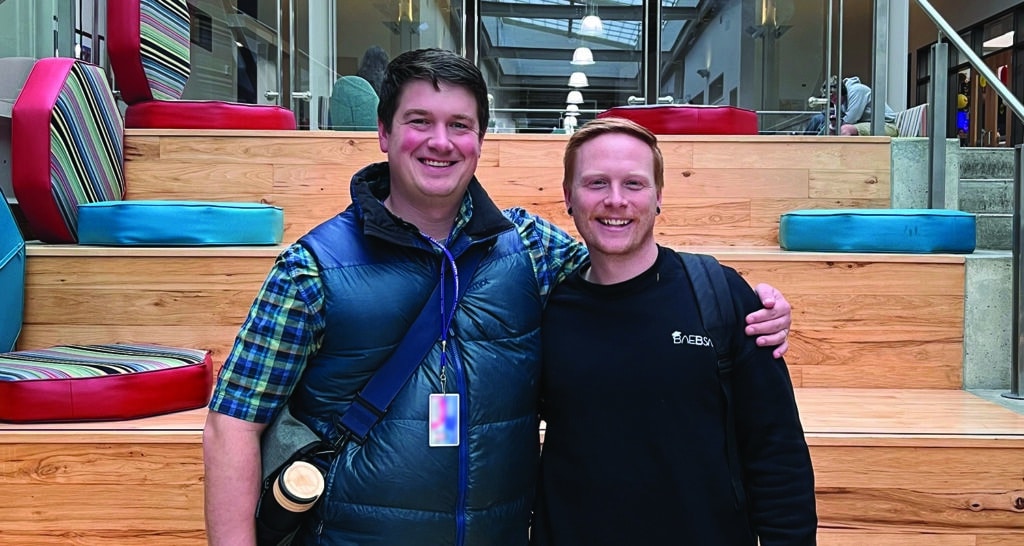 Two navigator men, who lead the Austin Community College ministry, stand next to each other infront of a large staircase.