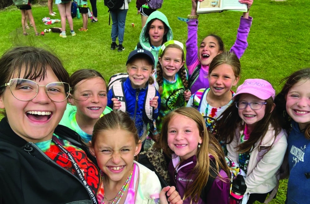 A group of kids from Eagle Lake Camp stand with their camp counselor.