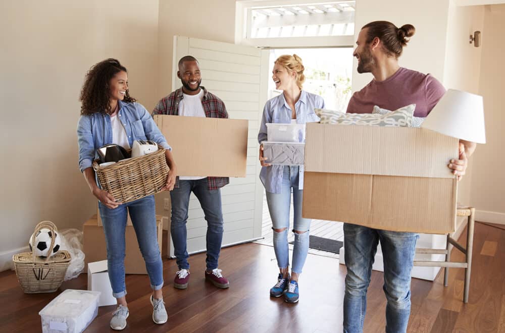 Friends help a couple to carry boxes into new home on moving day.