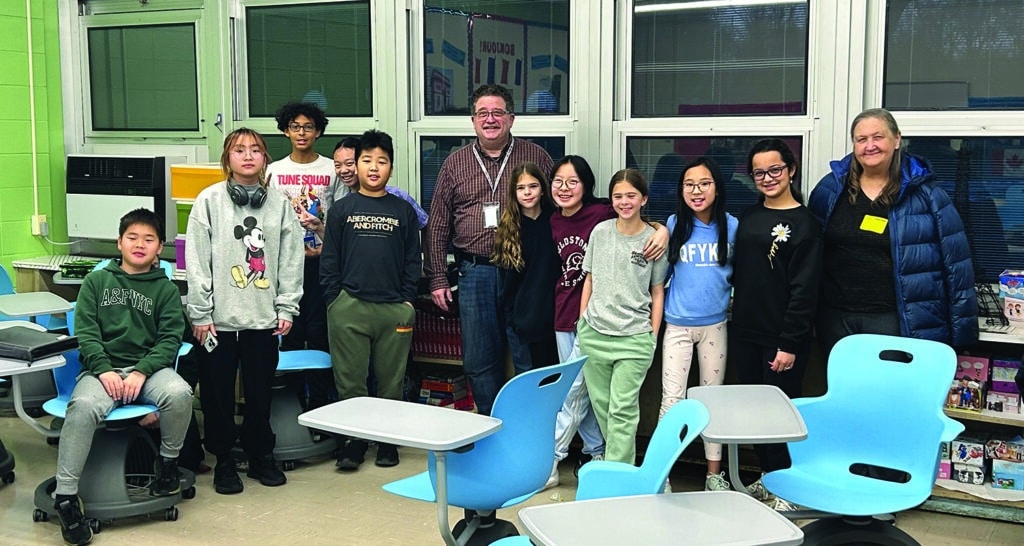 A group photo of middle school students in a classroom, participating in a Navigators Bible club.