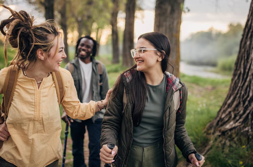 Three people, man and two women hikers taking a walk in nature together.