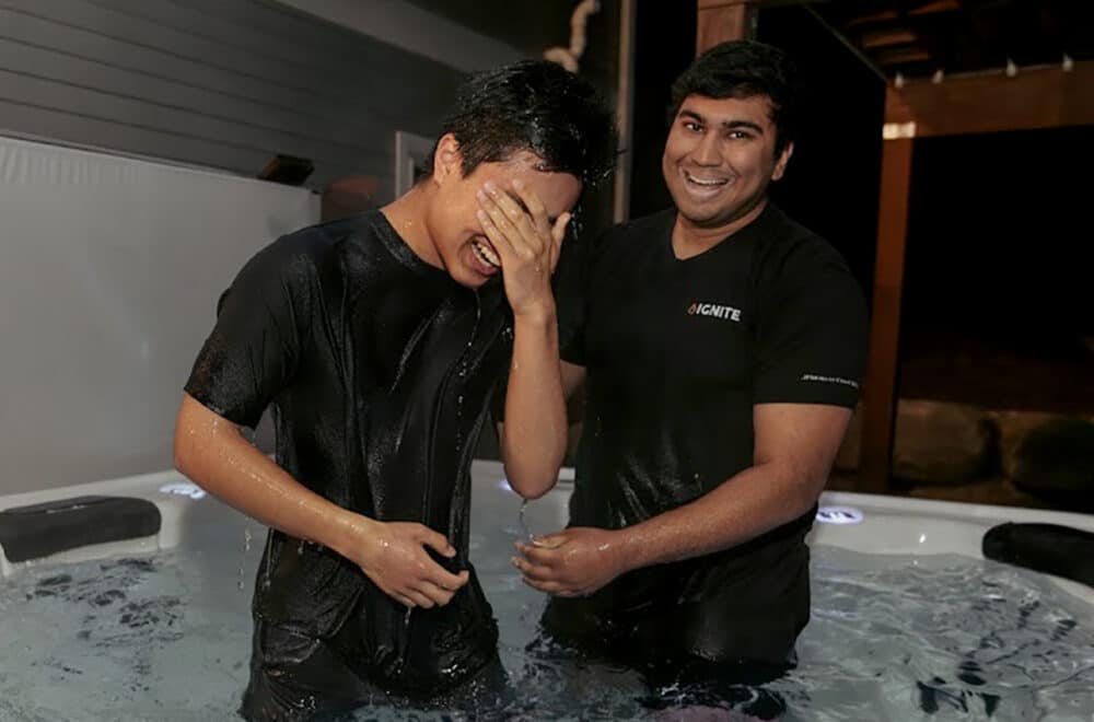 Two men standing in a small pool smiling after a baptism.