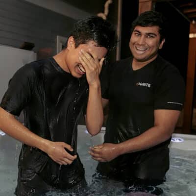 Two men standing in a small pool smiling after a baptism.