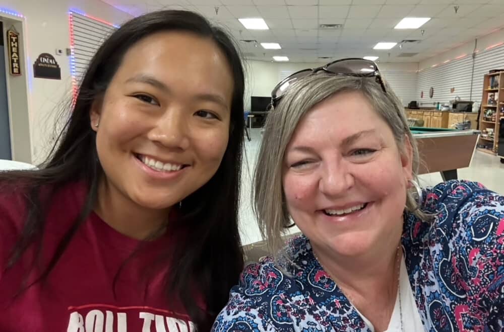 Two women smiling for a selfie indoors.